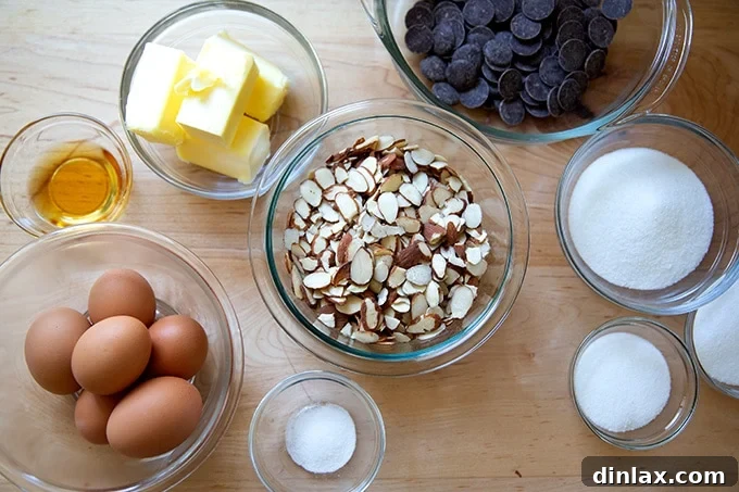 Classic Caprese Flourless Chocolate Almond Torte 3 All ingredients laid out on a kitchen counter for making Torta Caprese: whole almonds, sugar, dark chocolate, butter, eggs, salt, and Grand Marnier.