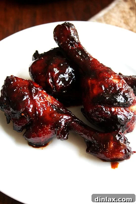 Sticky Honey-Soy Chicken 2 A plate of golden-brown honey-soy oven-baked chicken drumsticks, garnished with fresh herbs.