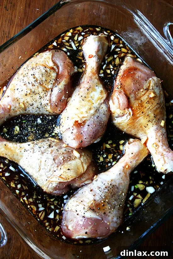 Sticky Honey-Soy Chicken 5 Chicken drumsticks arranged in a baking dish, completely covered in the rich honey-soy sauce mixture, ready for baking.