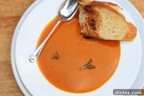 Rich Rosemary Butternut Bisque in a bowl, garnished with fresh rosemary and a swirl of cream