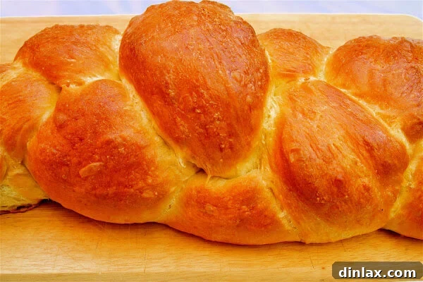 Freshly baked homemade challah bread, beautifully golden brown with sesame seeds, ready for slicing