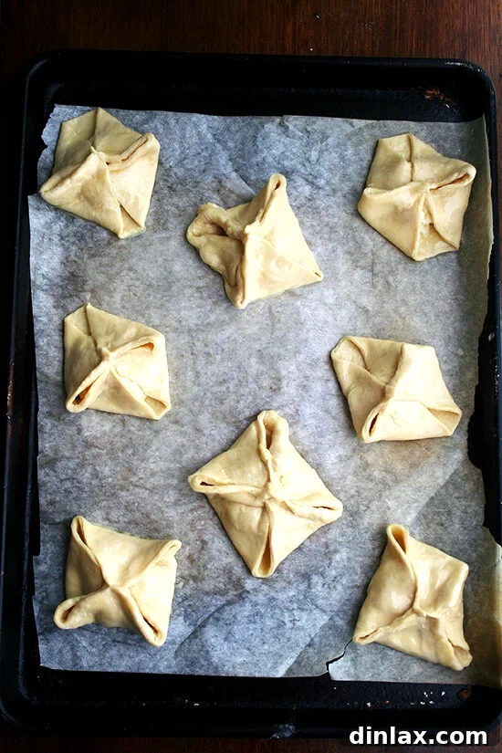 Eight egg-washed cheese Danishes, glistening and ready for their final rise, awaiting their transformation in the oven.