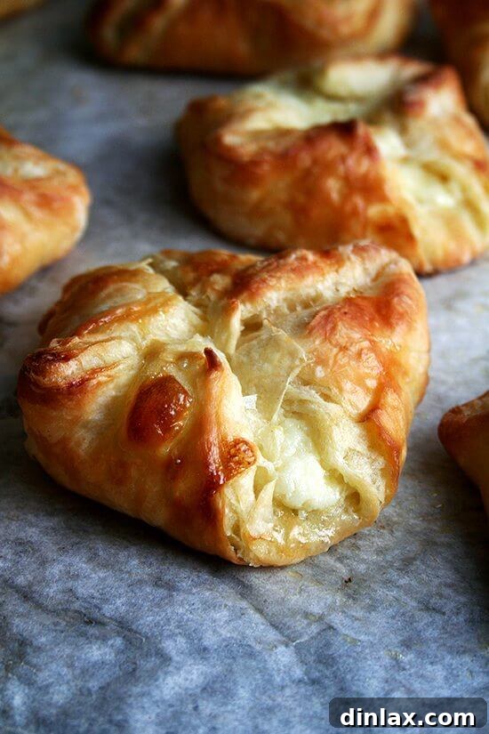 An up-close shot of golden-brown cheese Danishes resting on the baking sheet, their fluffy interior waiting to be revealed.