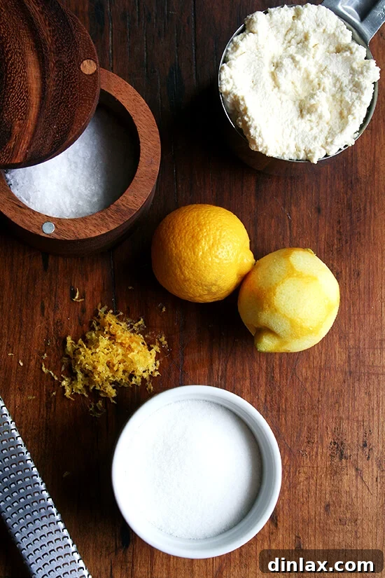 The lemon-ricotta filling ingredients, including fresh ricotta cheese, lemon, sugar, and salt, displayed on a wooden board.