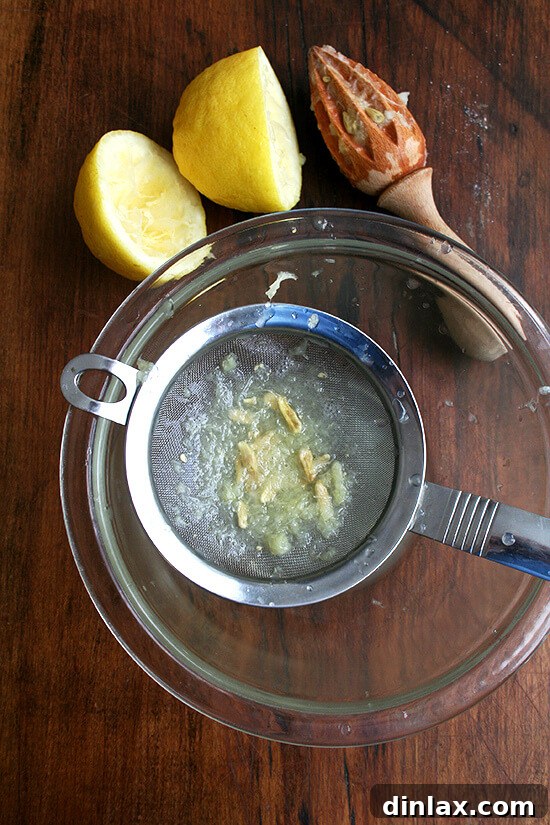 Silken Mascarpone Sorbet 3 Close-up of hands juicing a fresh lemon into a bowl, preparing the citrus component for the mascarpone sorbet recipe.