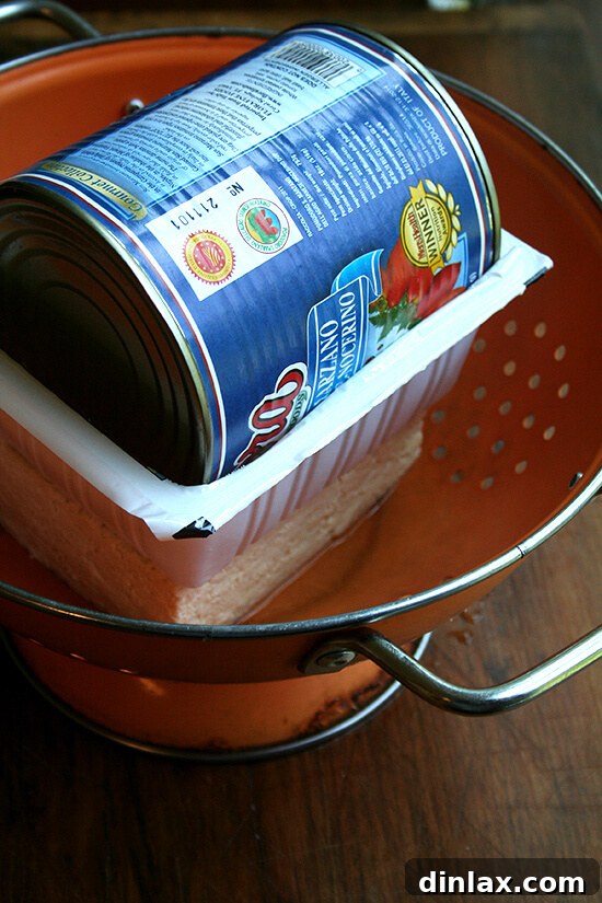 Preparing firm tofu for marination by pressing out excess water, a crucial step for maximum flavor absorption.