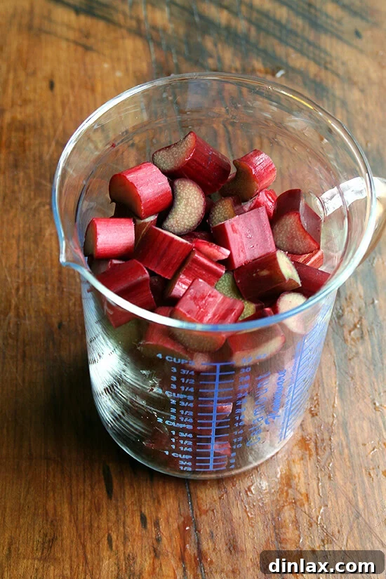 Jammy Rhubarb Ripple Ice Cream 6 A liquid measuring cup filled with vibrant red chopped rhubarb, indicating the precise quantity needed for the recipe.