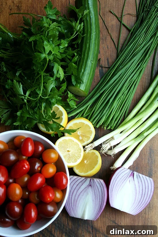 Fresh ingredients for tabbouleh salad laid out on a cutting board, including cucumbers, tomatoes, onions, and various herbs.