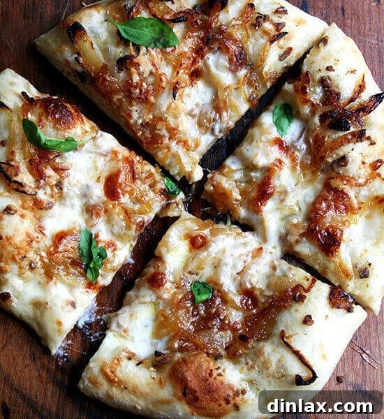 A golden-brown caramelized onion and burrata pizza, freshly baked and garnished with fresh basil.