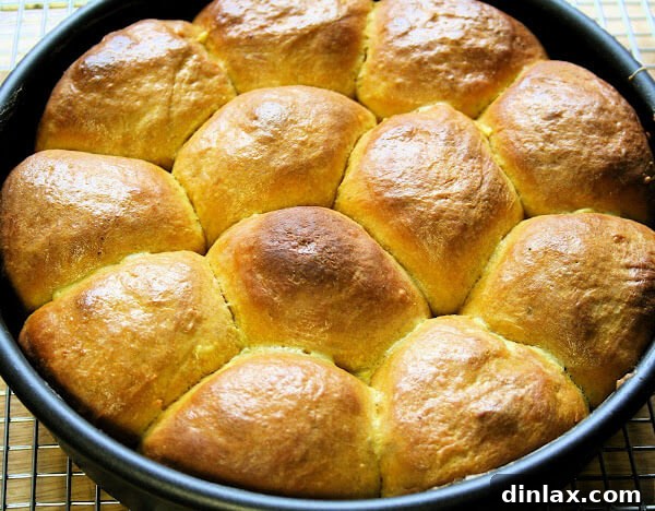 Freshly baked pumpkin dinner rolls cooling on a wire rack.