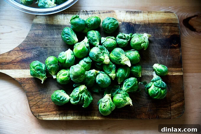 Fresh Brussels sprouts neatly arranged on a wooden cutting board, ready for preparation.