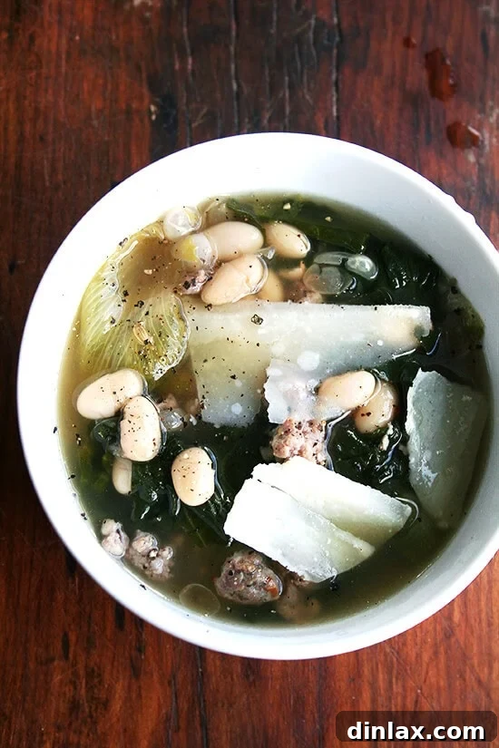 A comforting bowl of white bean, sausage, and escarole soup, perfect for a cold day, inspired by Italian culinary traditions. Hearty White Bean, Sausage, and Escarole Soup served in a bowl with crusty bread.