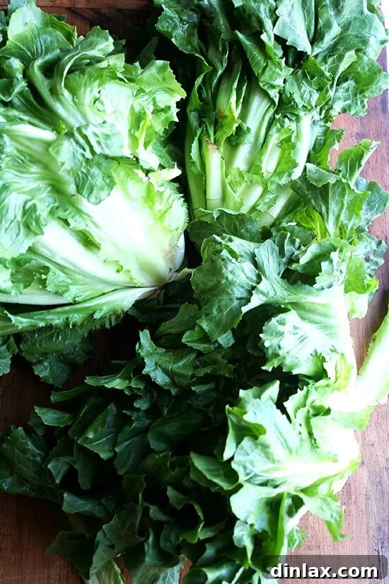 Hearty Italian Sausage, Escarole, and White Bean Soup 9 A clean cutting board with a head of fresh, vibrant green escarole, ready for preparation.