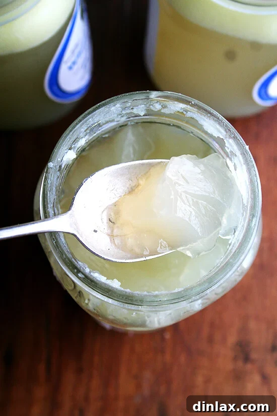 A close-up, overhead shot of a very thick and gelatinous homemade chicken stock, showcasing its concentrated richness.