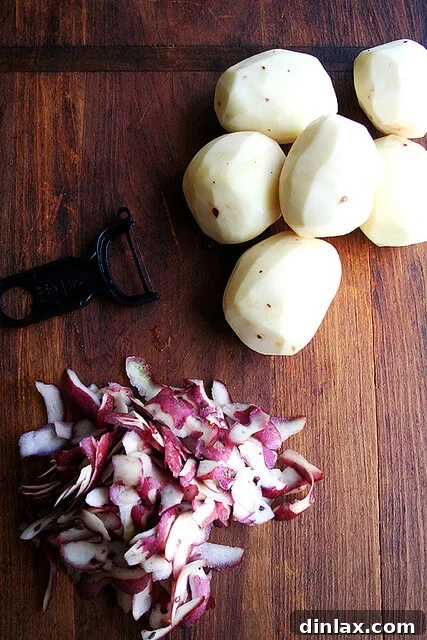 Alice Waters Perfected Potato Gratin 5 Close-up of peeled red potatoes on a cutting board, ready for slicing.