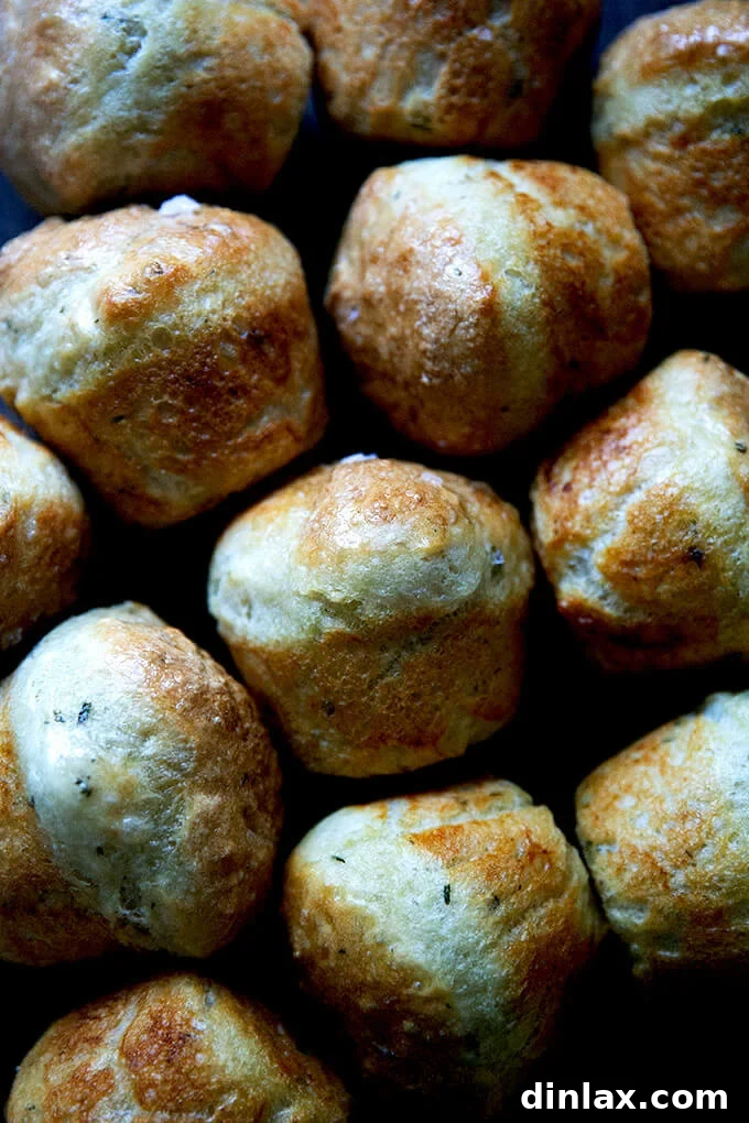 Thyme dinner rolls artfully arranged on a wooden serving board.