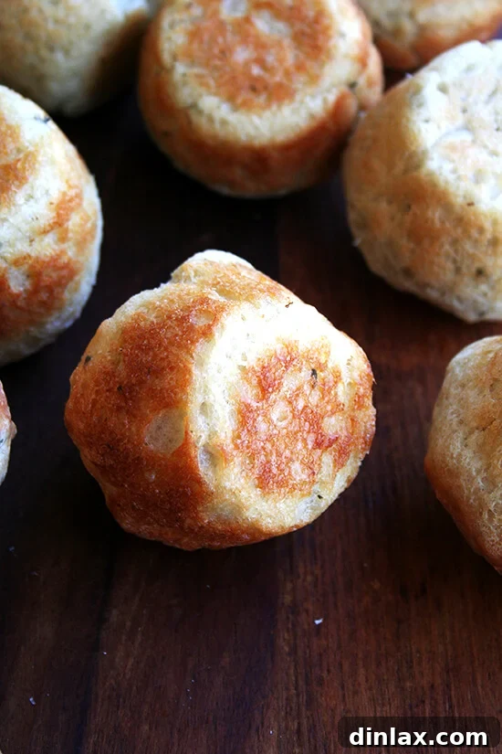 A generous pile of freshly baked thyme dinner rolls, golden and inviting.