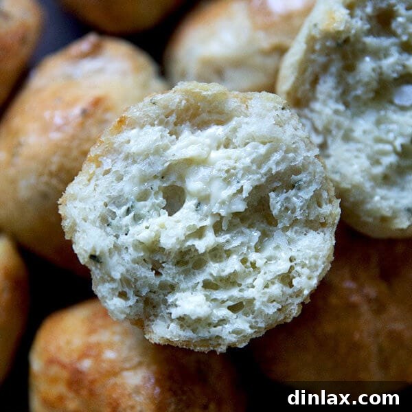 A beautifully halved and buttered thyme dinner roll, showcasing its soft interior and golden crust.