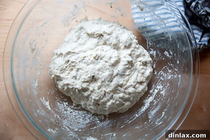 Just-mixed thyme dinner roll dough in a bowl, showing its sticky consistency.