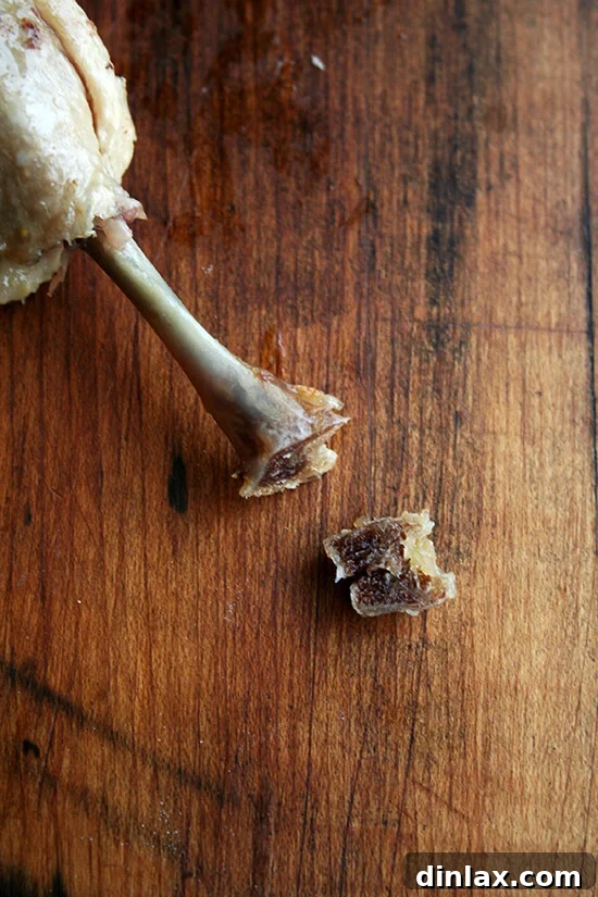 A cooked duck leg confit with excess fat carefully trimmed around the bone for a neater, more appealing appearance.