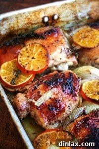 A roasting pan with roast chicken and clementines, ready to serve.