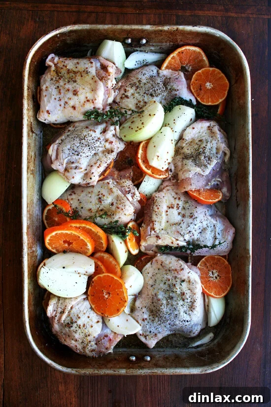 Clementine-Kissed Roast Chicken 7 A roasting pan filled with sauced chicken and vegetables, halfway through cooking.