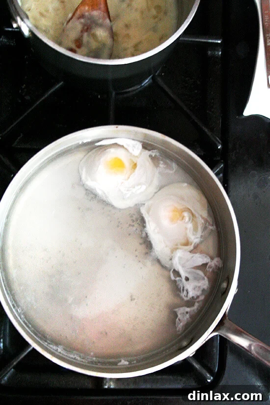 Two eggs poaching in a pot on the stovetop.
