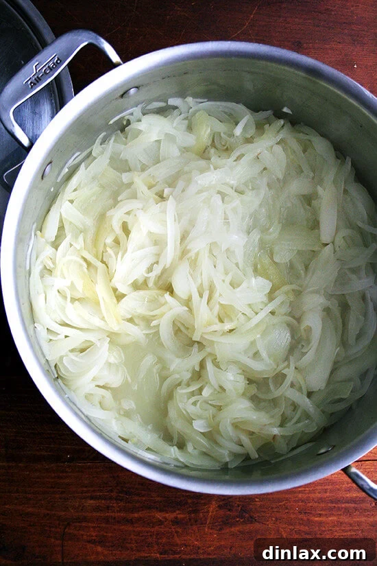 Onions, after 30 minutes of cooking, covered in a large pot, looking soft and moist.