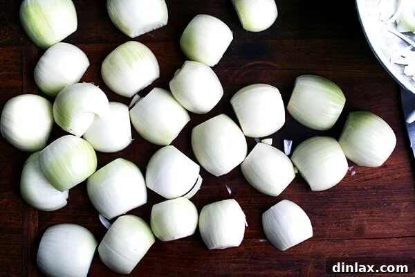 Multiple halved onions laid out on a cutting board.