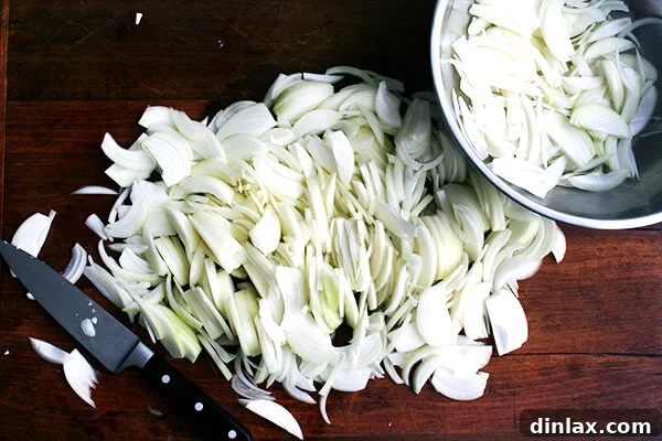 Six pounds of uniformly sliced onions on a large cutting board.