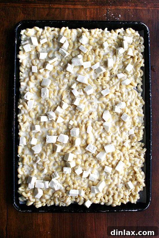 Golden Crispy Macaroni Cheese Bake 9 Diced fresh mozzarella cubes being sprinkled over the mac n cheese layer on the sheet pan