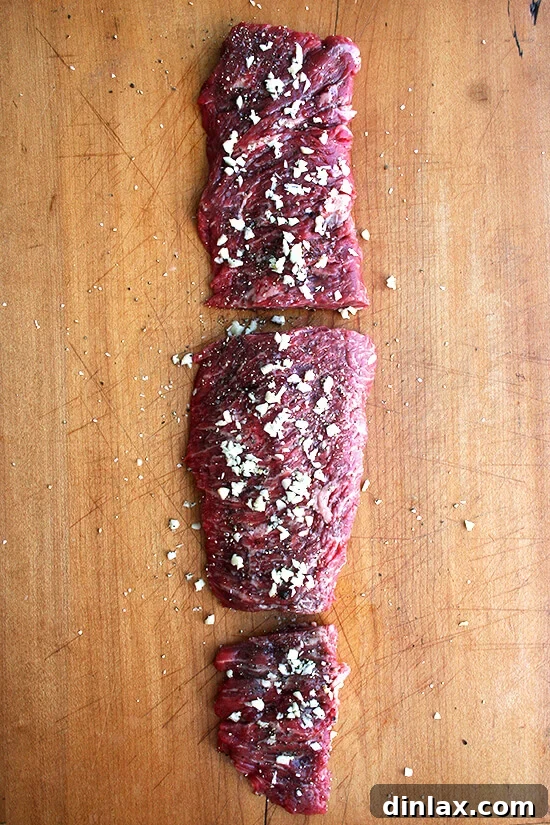 Flap steak seasoned with salt, pepper, and garlic, ready for searing.