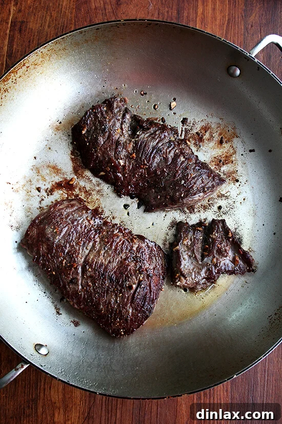 Sizzling flap steak searing in a hot skillet, developing a perfect crust.
