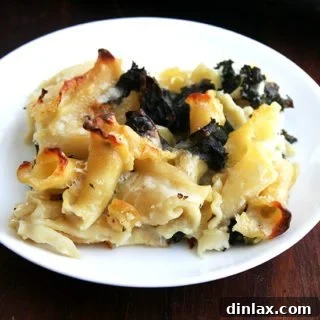 A plate of sheet pan pasta gratin with kale, served with a fork.