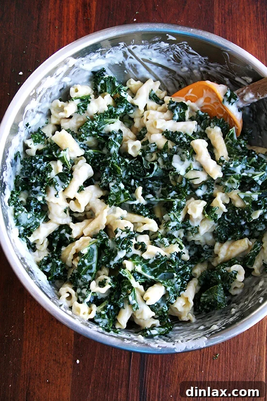 All ingredients, including pasta, béchamel, kale, and cheese, thoroughly mixed together in a large bowl.