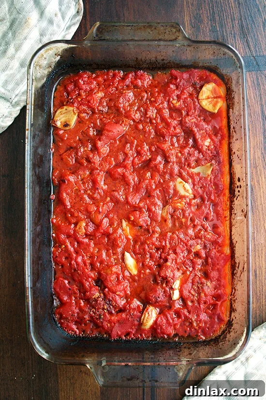 Roasted with butter, anchovies and a lot of garlic, canned tomatoes transform into an incredibly tasty, easy-to-make, all-purpose tomato sauce. The dish is shown pre-roasting with all ingredients combined.
