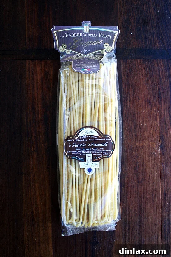 Cooked bucatini pasta being tossed with the butter-roasted tomato sauce.