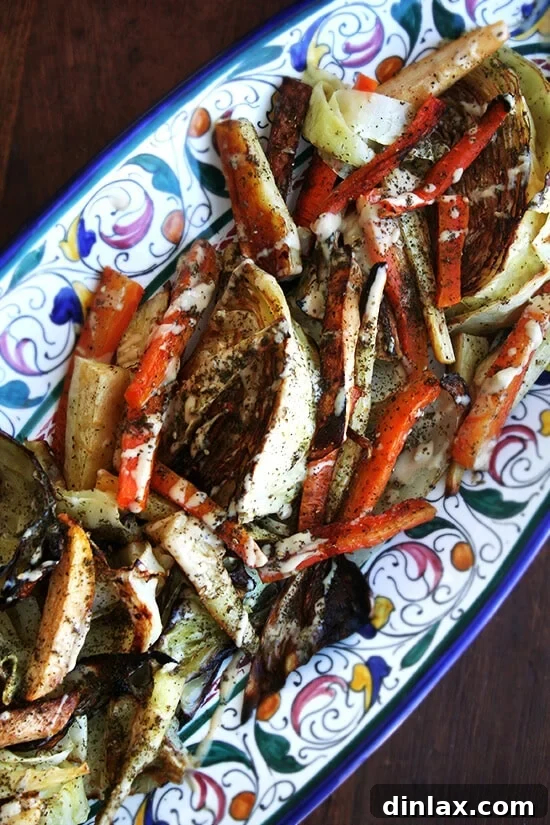 A vibrant platter of perfectly roasted vegetables, including cauliflower, broccoli, carrots, and parsnips, drizzled with a rich tahini, olive oil, lemon juice, and garlic dressing, finished with za'atar.