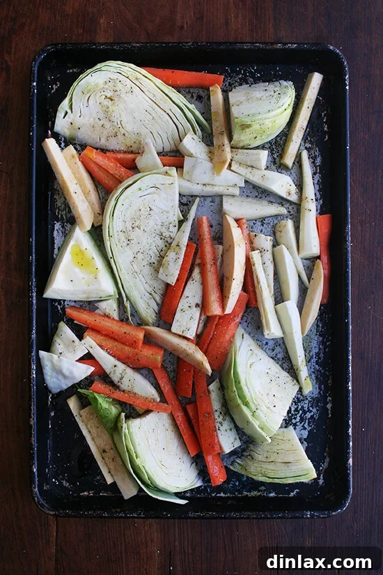 Vegetables spread evenly on a sheet pan, seasoned and drizzled with olive oil, ready for the oven.