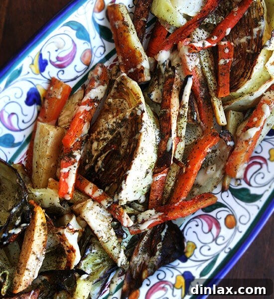 A vibrant platter of perfectly roasted vegetables, including cauliflower, broccoli, carrots, and parsnips, drizzled with a rich tahini, olive oil, lemon juice, and garlic dressing, finished with za'atar.