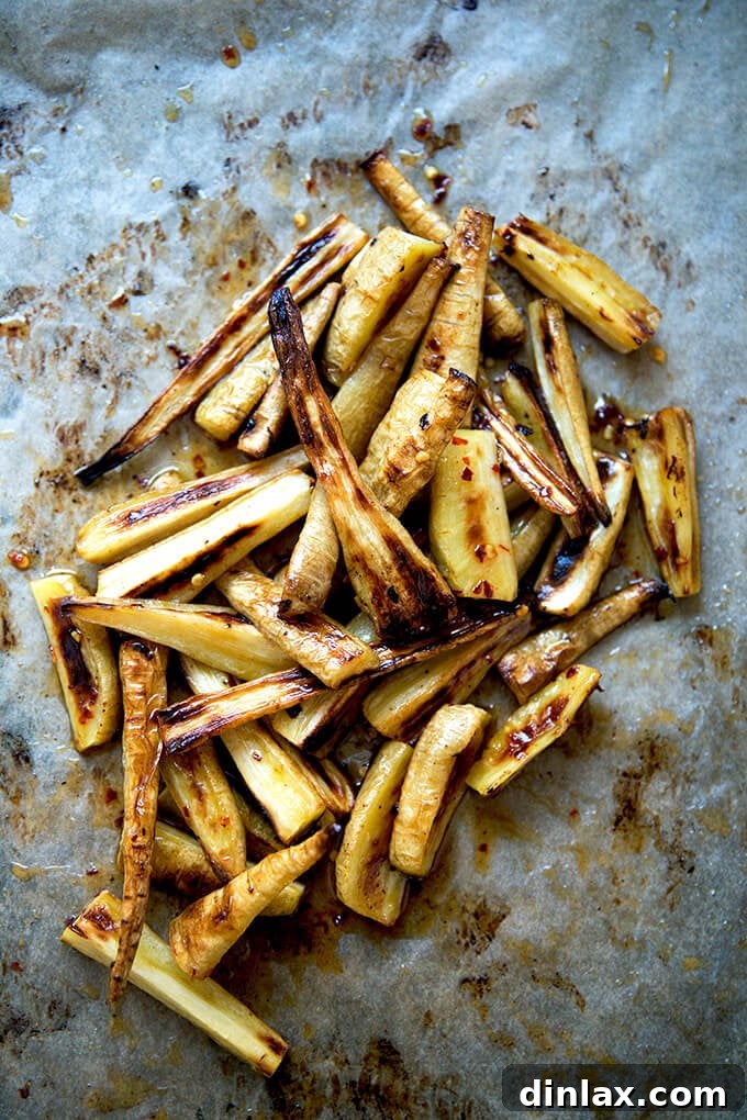 Roasted Chili-Honey Parsnips 7 A sheet pan of just-roasted parsnips being generously coated with the glistening, warm chile-honey butter, ensuring every piece is infused with flavor.