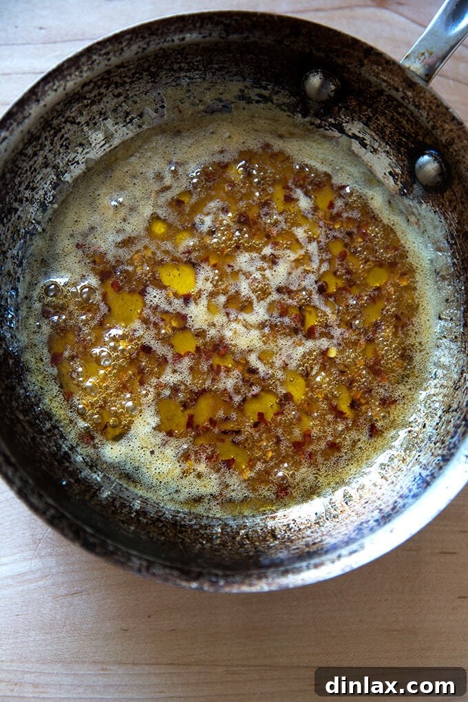 Roasted Chili-Honey Parsnips 4 A small saucepan containing the melted chile-honey butter, sparkling with crushed red pepper flakes, ready for tossing with roasted parsnips.