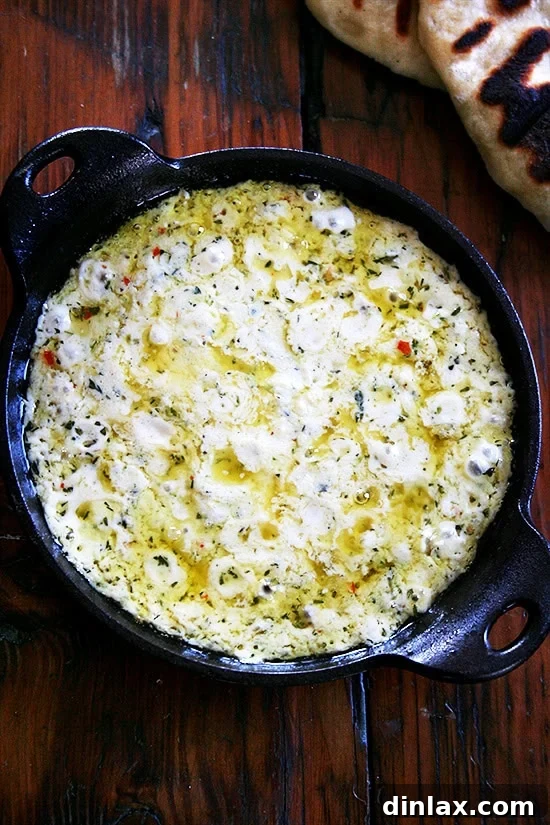A beautifully golden-brown baked ricotta dip, garnished with fresh thyme, served with crusty bread for dipping. It's a perfect appetizer for any gathering.