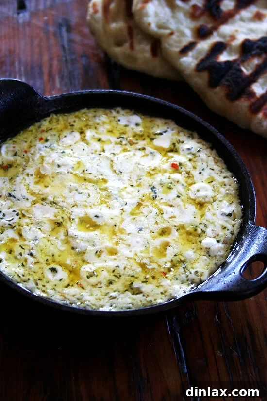 A close-up shot of the baked ricotta, golden and bubbling, fresh out of the oven, revealing its creamy texture and herb flecks.