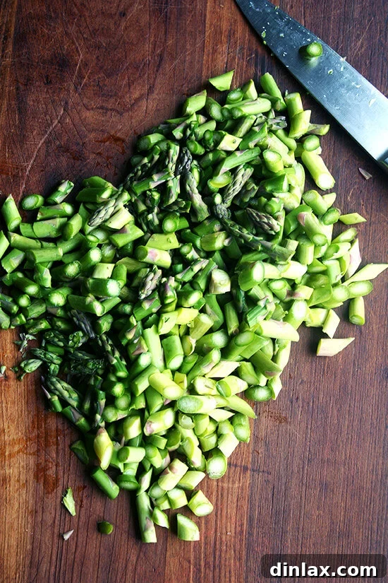 Vibrant Spring Wheat Berry Salad 3 Fresh asparagus spears being cut on the bias into small, bite-sized pieces for the salad.
