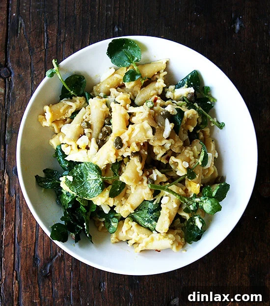 A vibrant campanelle pasta dish featuring a warm anchovy-caper-olive oil sauce, freshly chopped hard-boiled eggs, and crisp greens, perfectly dressed for a satisfying impromptu dinner.
