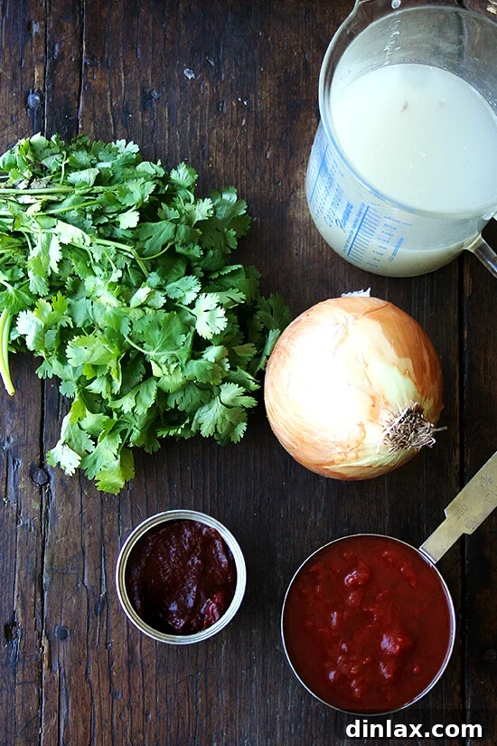 Spicy Smoky Chicken Tinga Tacos 2 A vibrant collection of ingredients for homemade chicken tinga laid out on a wooden surface.