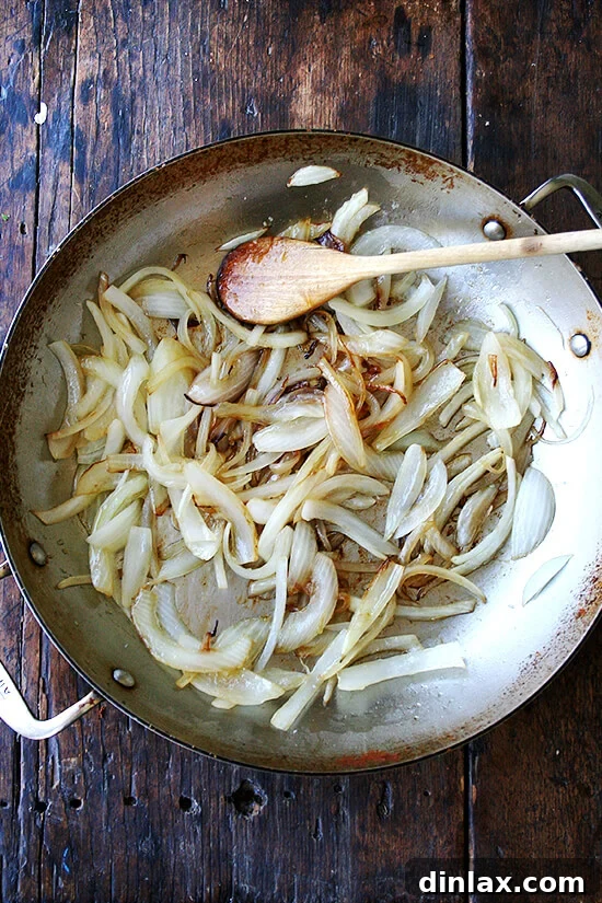 Spicy Smoky Chicken Tinga Tacos 4 A skilled chef sautéing sliced white onions until golden and translucent.