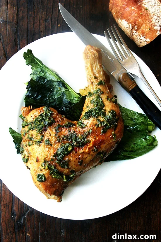 A plate of perfectly crispy, herby roasted chicken pieces served over a bed of vibrant mustard greens. The chicken skin is golden brown and crackling, and the dish is garnished with fresh herbs, inviting a delightful culinary experience.