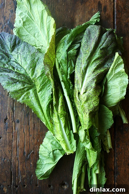 A fresh pile of vibrant green mustard greens, showcasing their tender leaves, ready to be served alongside the roasted chicken.